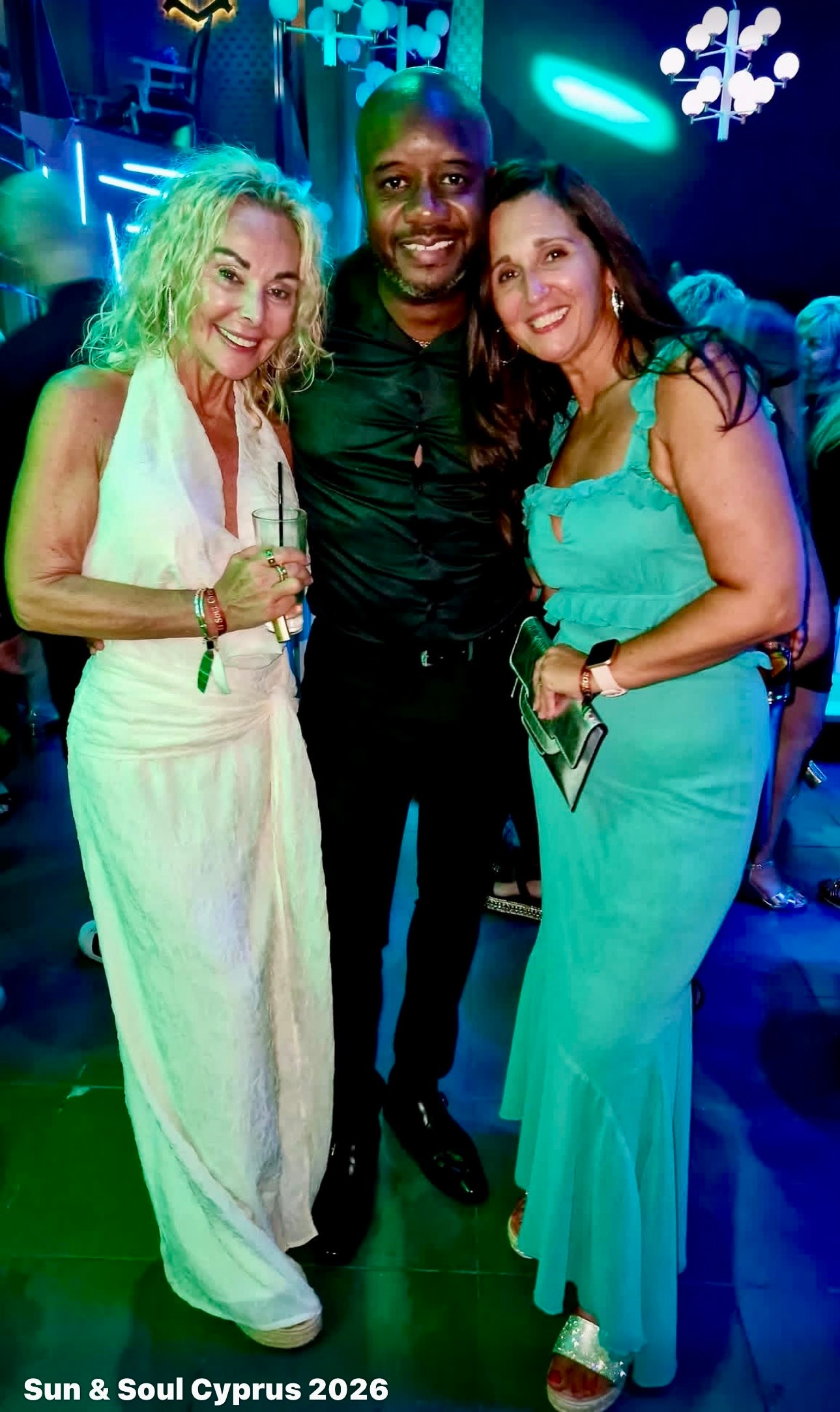 Three guests posing together under neon lights at Sun & Soul Cyprus 2026